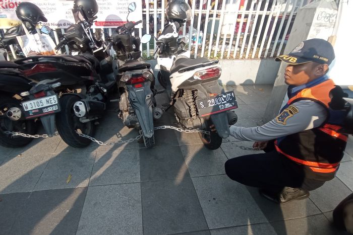 CEKREK: Petugas Dishub Surabaya memberedel sepeda motor yang kedapatan parkir di tepat parkir liar di Surabaya.