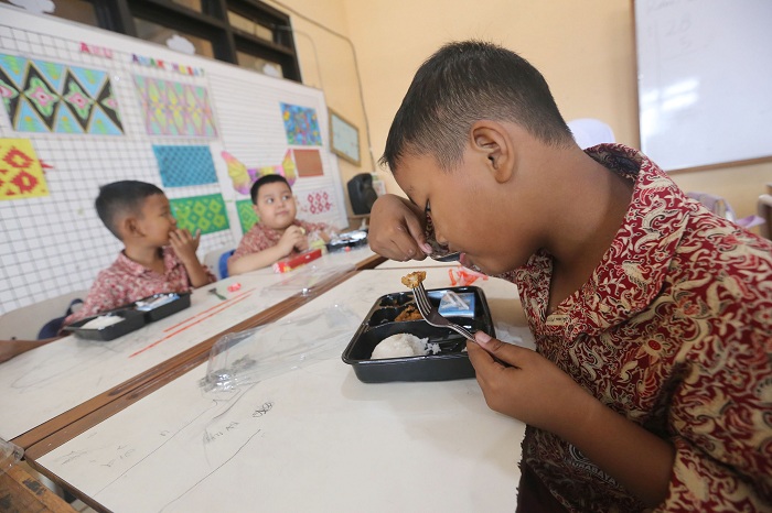 NIKMAT: Tiga siswa SD di Surabaya menyantap sajian program Makan Bergizi Gratis.