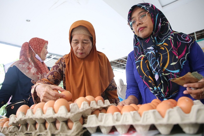 BELANJA: Dua perempuan memilih telur yang akan dibelinya. Pemerintah terus berupaya dengan berbagai cara untuk mendongkrak daya beli masyarakat.