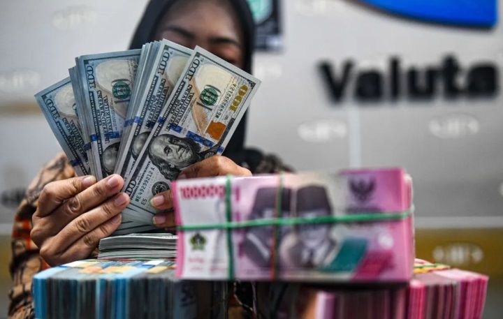 HITUNG: Seorang karyawan money changer meneliti setiap lembaran rupiah yang akan ditukakan dengan dolar Amerika Serikat.