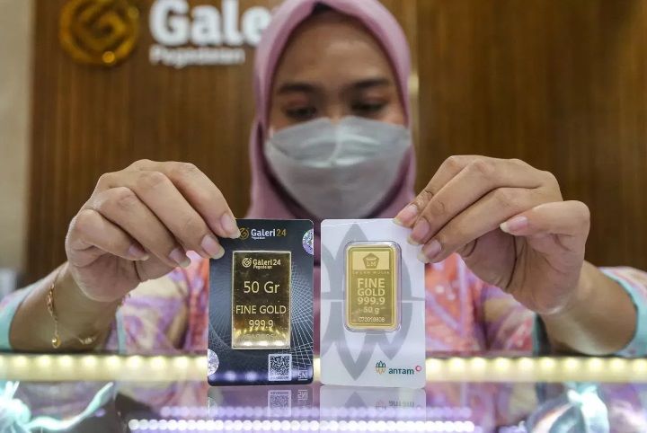 INVESTASI: Salah satu karyawan butik emas menunjukkan dua kepingan logam mulia Antam.