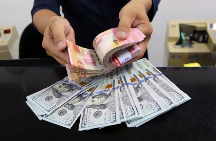 HITUNG: Seorang karyawan money changer meneliti setiap lembaran rupiah yang akan ditukarkan dengan dolar Amerika Serikat.