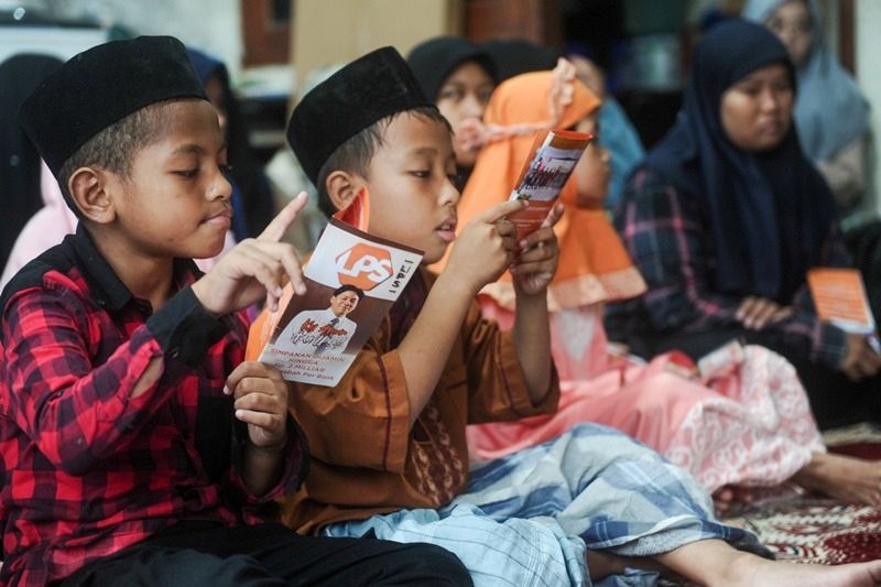 SERIUS: Dua bocah Panti Asuhan Al Ikhsan Surabaya tampak serius membaca flyer LPS dalam kegiatan sosial kemasyarakatan yang digelar, Minggu (23/3/2025).