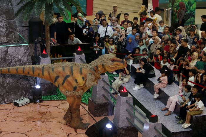DINOSAURUS: Sejumlah pengunjung melihat pertunjukan langsung dinosaurus, dalam wahana Dino Island School Holiday, yang digelar di Atrium Royal Plaza Surabaya, Minggu (22/6).