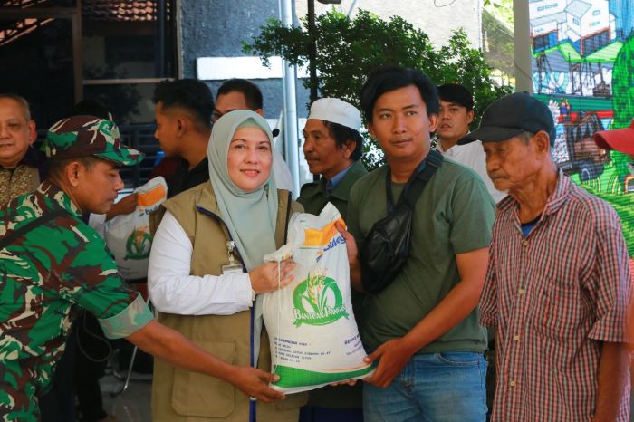 BANTUAN: Wakil Pimpinan Wilayah Bulog Jatim Cory Trisilawaty didampingi anggota TNI saat menyerahkan bantuan beras kepada Keluarga Penerima Manfaat.