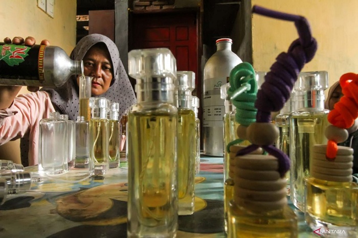 HATI-HATI: Pengusaha UMKM mengisi parfum dari bahan baku minyak nilam ke dalam botol kemasan.