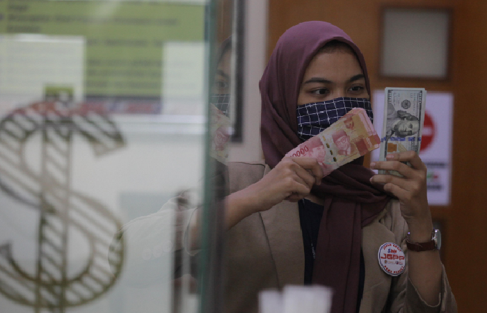 ILUSTRASI: Seorang karyawan menunjukkan mata uang rupiah dan dolar Amerika Serikat di sebuah konter money changer.
