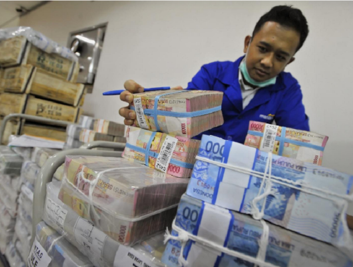 ILUSTRASI: Salah satu petugas bank plat merah sedang menata tumpukan rupiah dalam berbagai macam nilai.