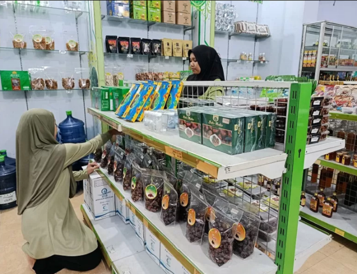 PELUANG: Dua karyawan sedang menata etalase toko perlengkapan dan oleh-oleh haji serta umrah.