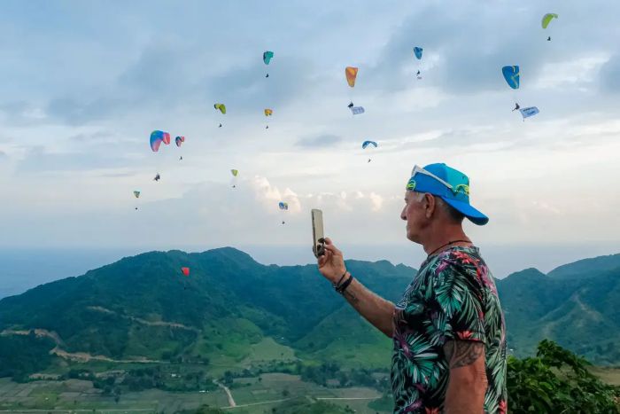 INDAH: Turis asing mengabadikan ajang sport tourism bertajuk Paragliding Accuracy World Cup 2025 yang digelar di Sky Lancing Lombok Paragliding, Lombok Tengah
