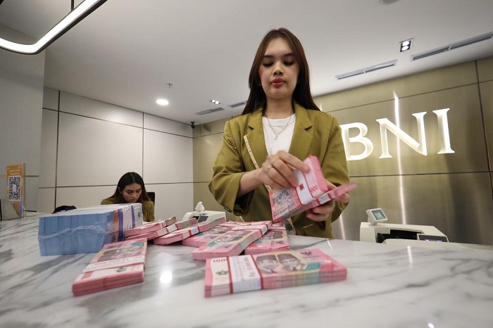 ILUSTRASI: Teller BNI sedang menghitung uang kertas pecahan Rp 100.000. Bank Indonesia mencatat uang beredar dalam arti luas (M2) naik menjadi Rp 10.117,8 triliun per Januari 2026.