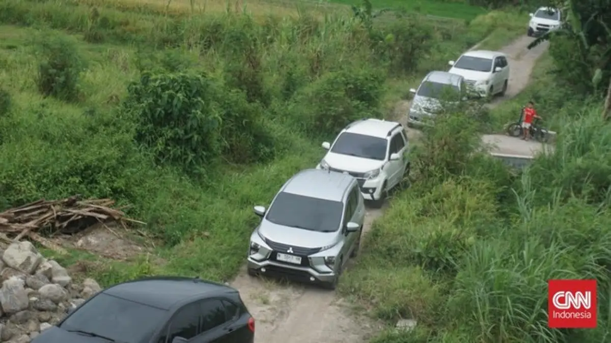 Barisan mobil pemudik terjebak di jalan sempit area persawahan di Sleman saat mencoba menuju akses fungsional Tol Jogja-Solo melalui panduan aplikasi navigasi digital.
