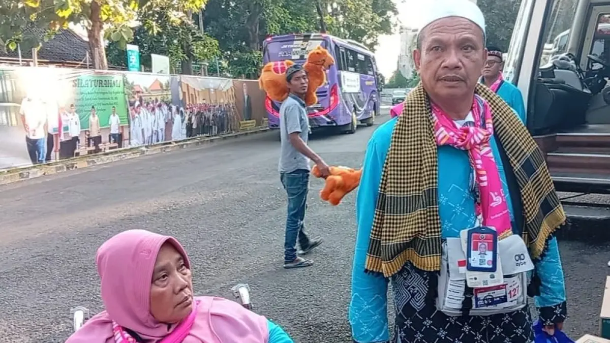 SEMBUH: Mat Heni sembuh dari penyakit stroke setelah tiba di Tanah Suci. Ia tampak didampingi istrinya, Muntiani Maskor, di Asrama Haji Debarkasi Surabaya.(Foto: Rahmat Sudrajat/Radar Surabaya)