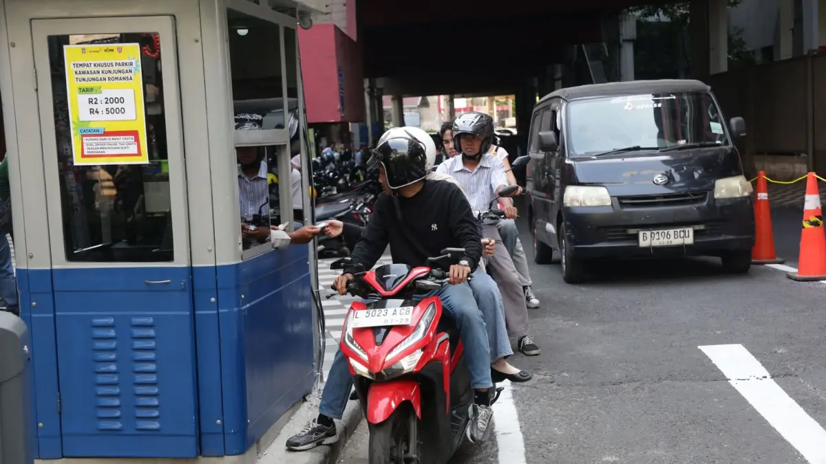 Pengendara motor mengambil tiket di gate parkir elektronik Jalan Tanjung Anom, Surabaya.