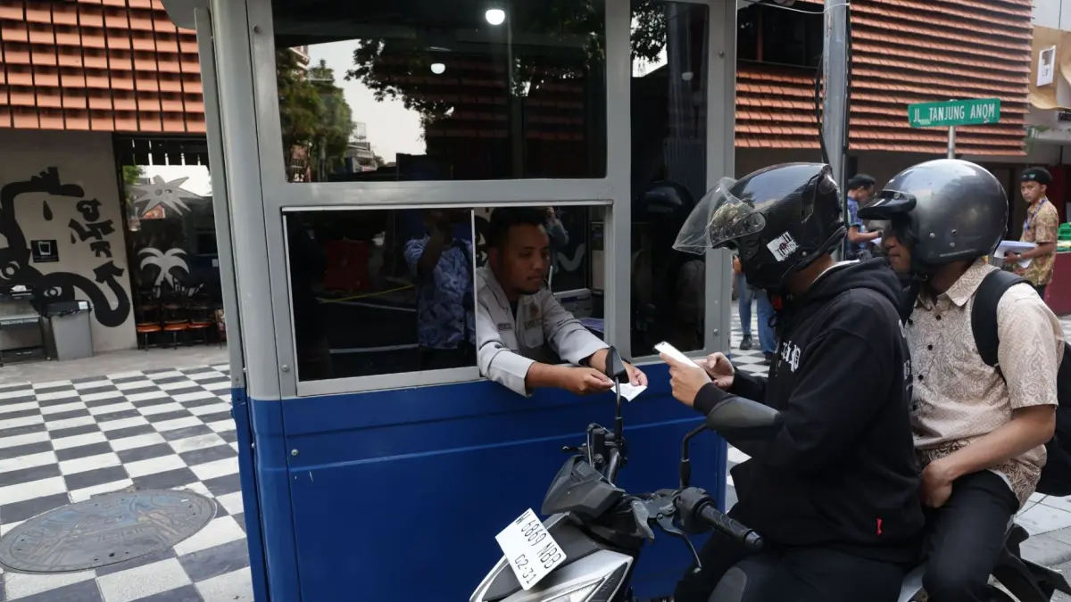 Pengendara motor melakukan transaksi non-tunai di gerbang parkir digital Tanjung Anom Surabaya.