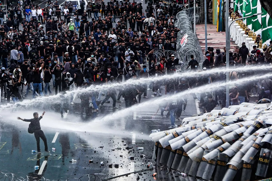 Polisi menyemprotkan air dari water canon untuk menghalau sejumlah pengunjuk rasa yang beraksi untuk menyikapi UU TNI di Surabaya, Jawa Timur, Senin (24/3/2025).