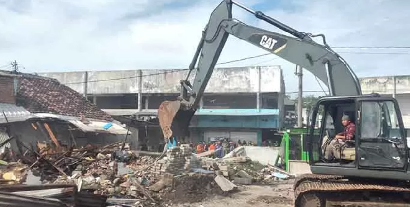 MELANGGAR: Salah satu lapak pedagang di lingkungan Pasar Besar dan Stasiun Pasuruan, dibongkar paksa menggunakan alat berat Senin (26/5).