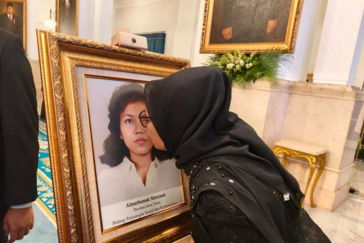 Adik Marsinah, Wijiati (54), mencium foto sang kakak seusai agenda Penganugerahan Pahlawan Nasional kepada Marsinah di Istana Negara, Jakarta, Senin (10/11/2025).