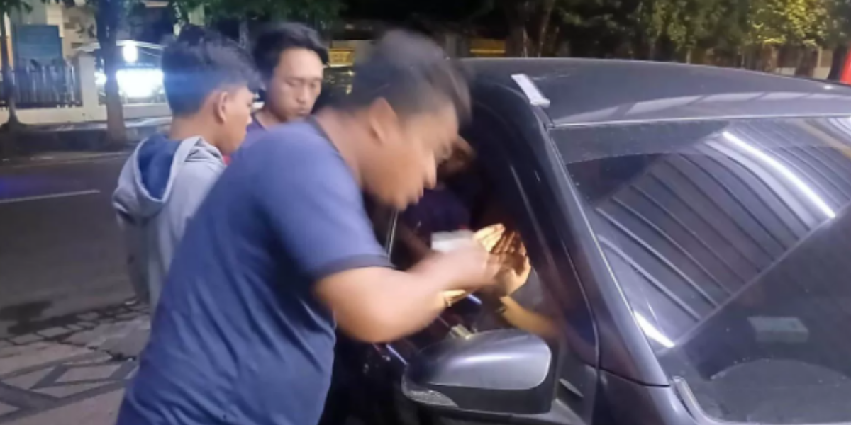 TERKUNCI: Petugas saat berusaha mengambil kunci mobil yang tertinggal di dalam kendaraan.