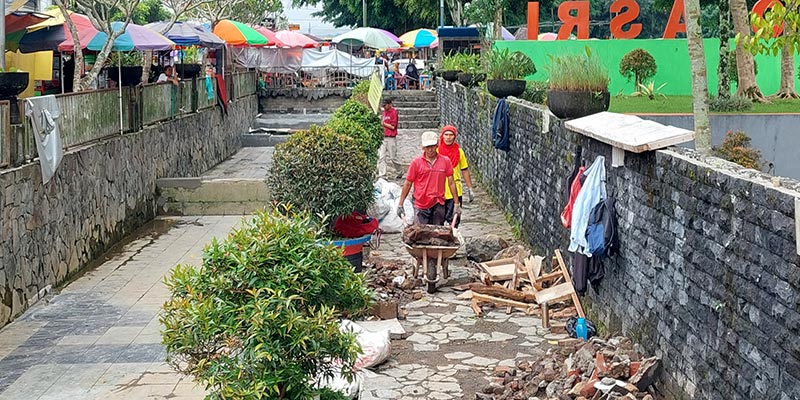 Para pekerja saat mengerjakan kolam ikan di pinggir trotoar jalan depan kantor Arpusda, Jumat (7/7/2023).