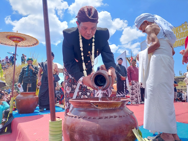 Kepala Desa Purbosari Pujiono menuangkan air yang telah diritual ke dalam guci saat ritual merti tirta amerta bumi, Minggu (15/10/2023).