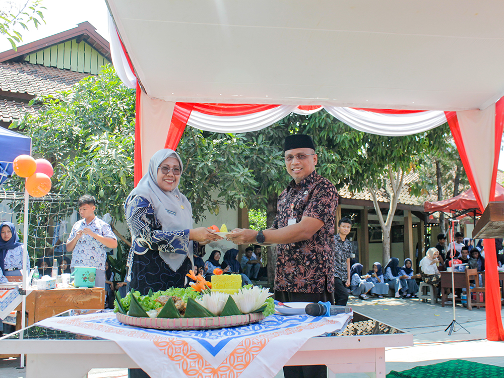 Kasi SMA Cabang Dinas Pendidikan Wilayah 8 Aris Goetomo Danuwarsito SE menyerahkan potongan tumpeng kepada Kepala SMA Negeri 1 Ngluwar Beny Sukandari.