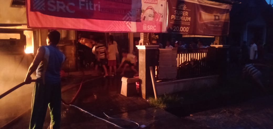 Petugas pemadam kebakaran Kabupaten Magelang saat menjinakkan api yang membakar rumah dan toko di Desa Rejosari, Bandongan.