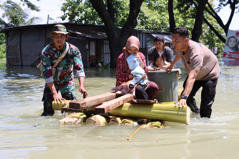 Petugas gabungan mengevakuasi warga dengan getek pohon pisang di Jalan Pantura Karanganyar, Kabupaten Demak yang masih terendam banjir, Jumat (9/2/2024).