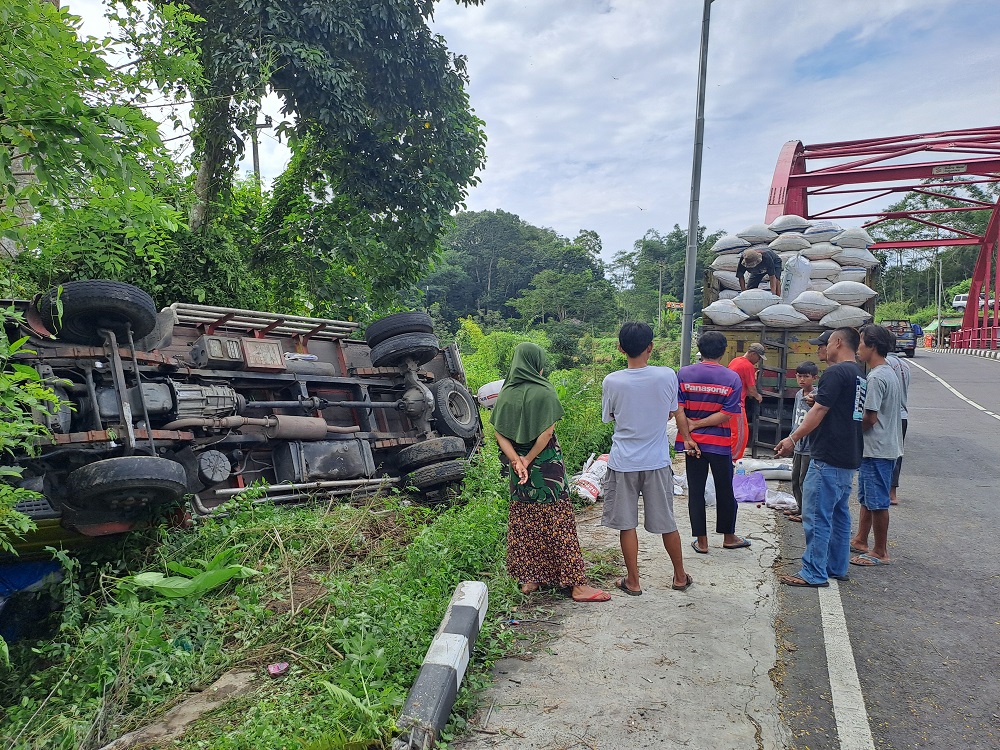 Truk bermuatan pupuk terguling di bibir jurang di Sungai Biru, Bandongan, Kabupaten Magelang, setelah as roda patah, Senin (11/3/2024) pagi.