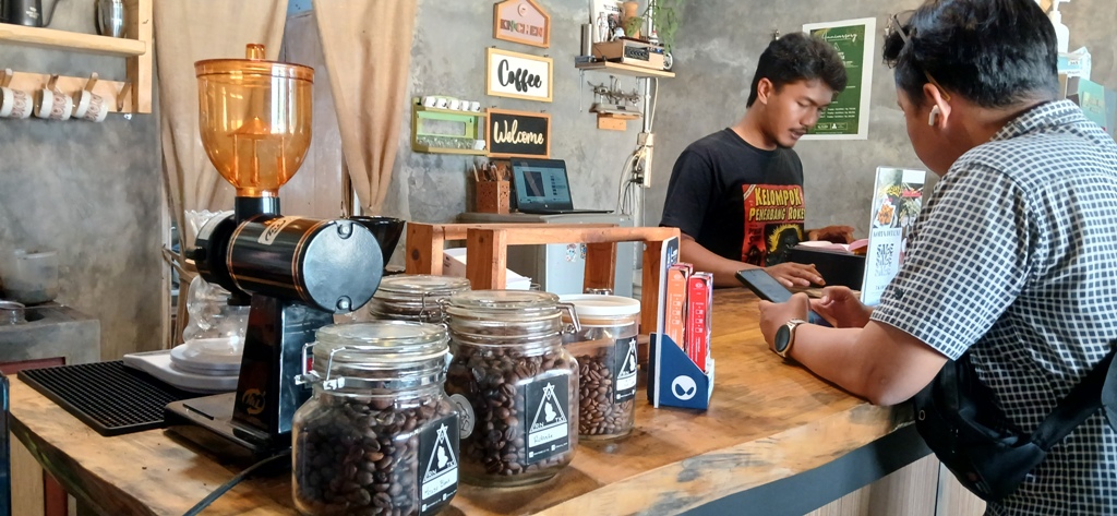 Ridho Dwi Putro tengah melayani pembeli di kedai kopinya.