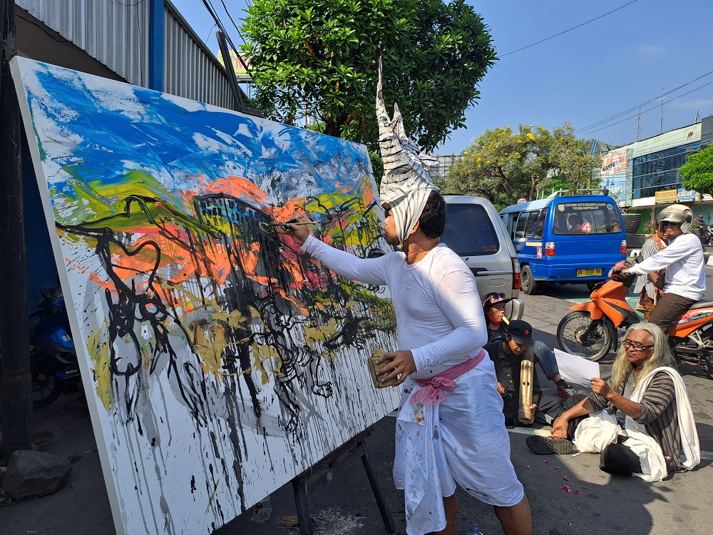 Seniman Asal Bali Made Arya Dwita Dedok saat melukis on the spot di depan gapura perempatan Pasar Rejowinangun, Kota Magelang, Senin (10/6/2024) pagi.