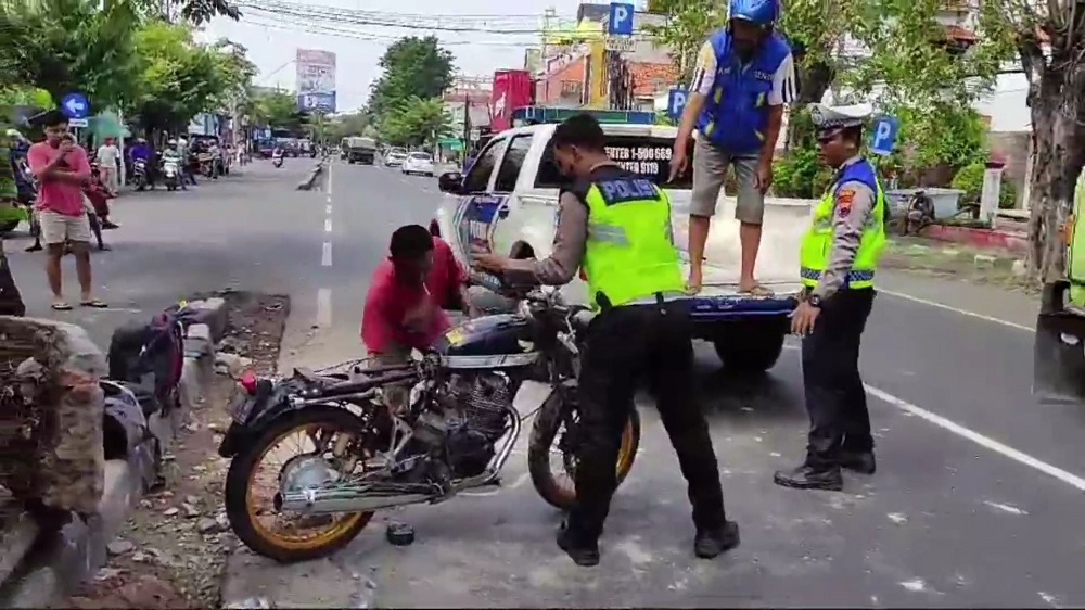 Petugas Satlantas Polres Kendal dibantu warga mengevakuasi sepeda motor Honda CB yang mengalami kecelakaan tunggal di Jalan Soekarno-Hatta, Senin (24/6/2024).