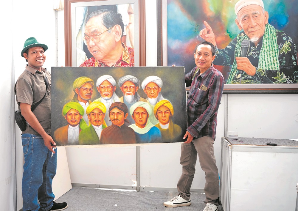Pelukis asal Demak, Mukhlison Jalembung bersama wartawan koran ini Wahib Pribadi menunjukkan lukisan Walisongo dalam pameran Demak Expo 2024.