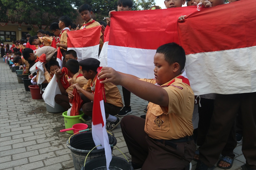 Siswa SDN Jatisari Kota Semarang mencuci bendera merah putih saat Kemah Karakter, Selasa (13/8/2024).