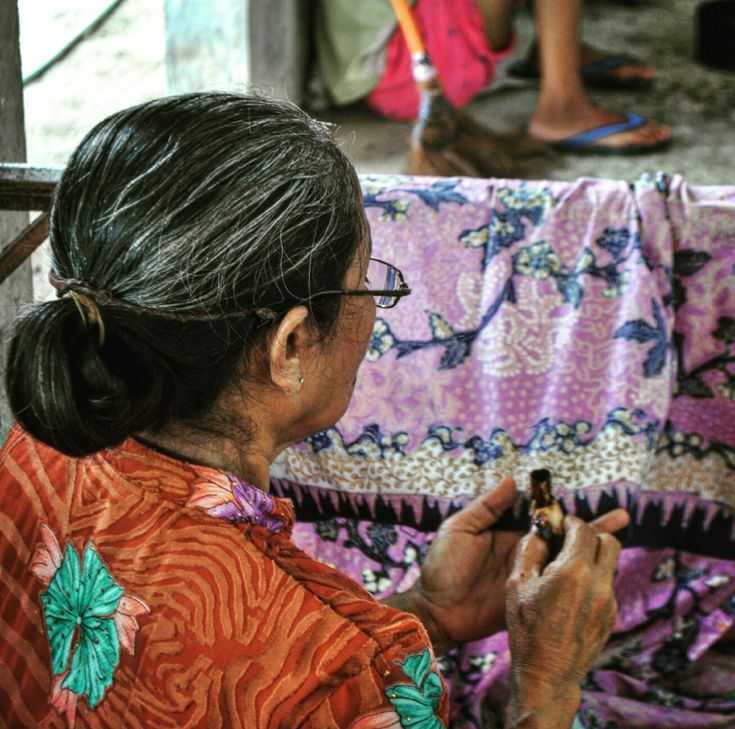 Seorang wanita sedang mecermati batik yang sudah dibuatnya