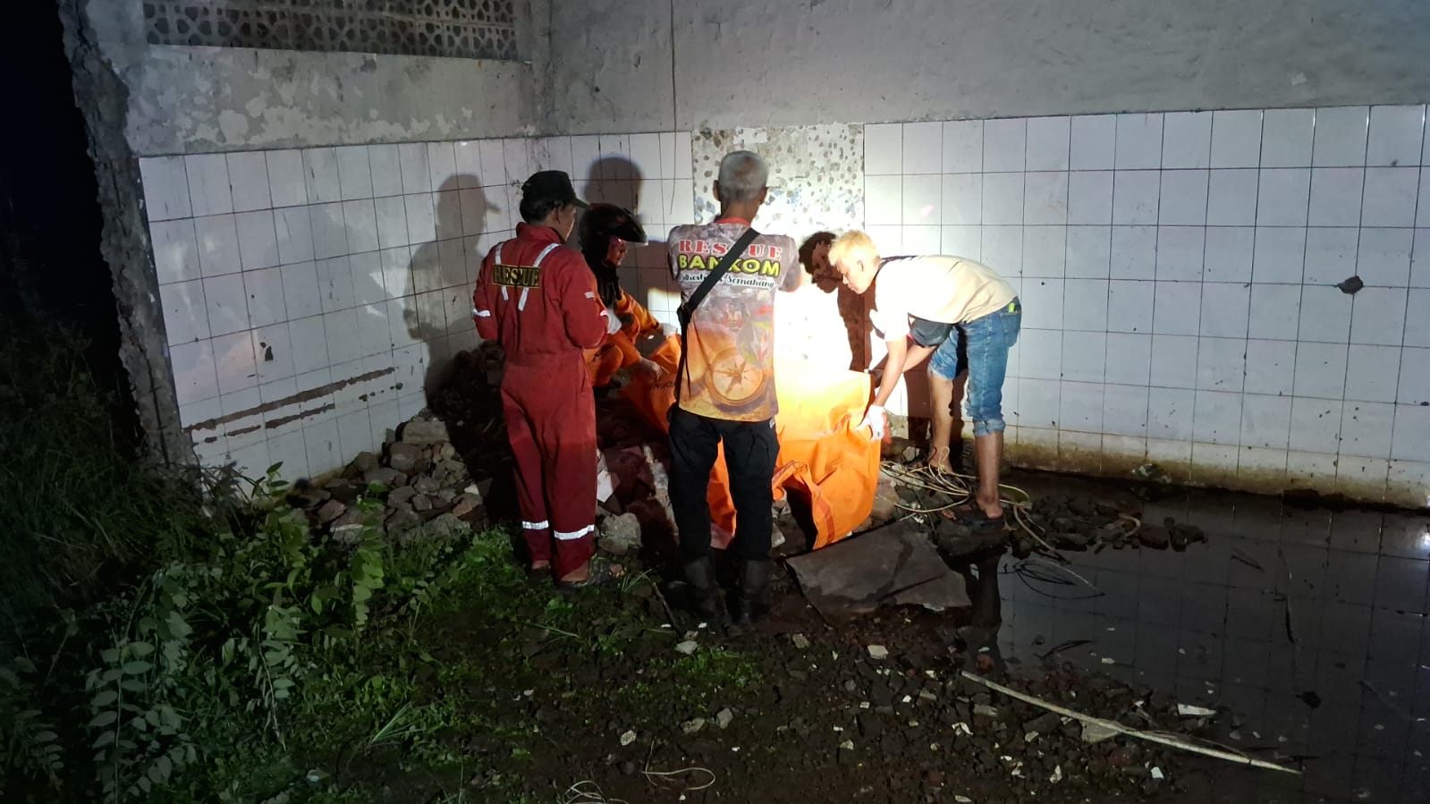 Petugas mengevakuasi sesosok mayat pria yang sudah membusuk di bekas kantor sebuah media  cetak di Jalan Raya Kaligawe, Genuk, Semarang, Senin (7/10/2024) malam sekitar pukul 19.45.