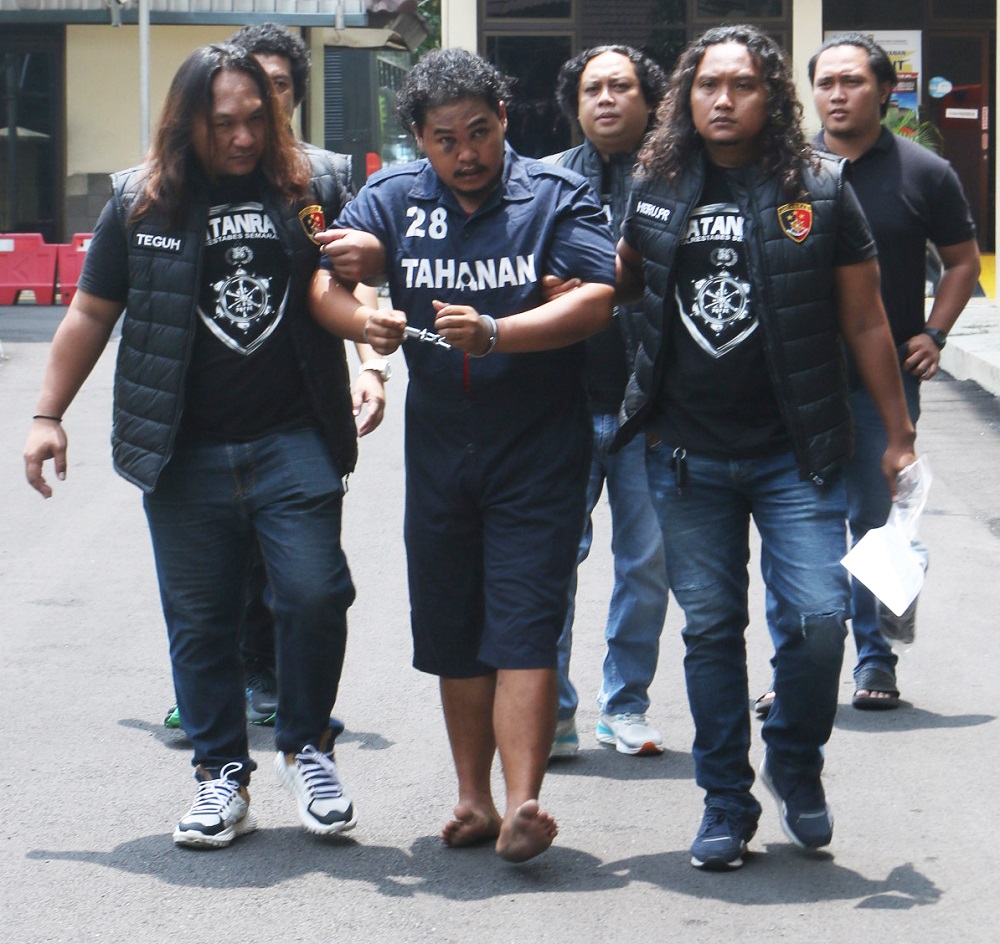 Tersangka Eko Prasetyo dibantu polisi untuk berjalan gara-gara kakinya ditembak ketika kabur saat akan ditangkap.