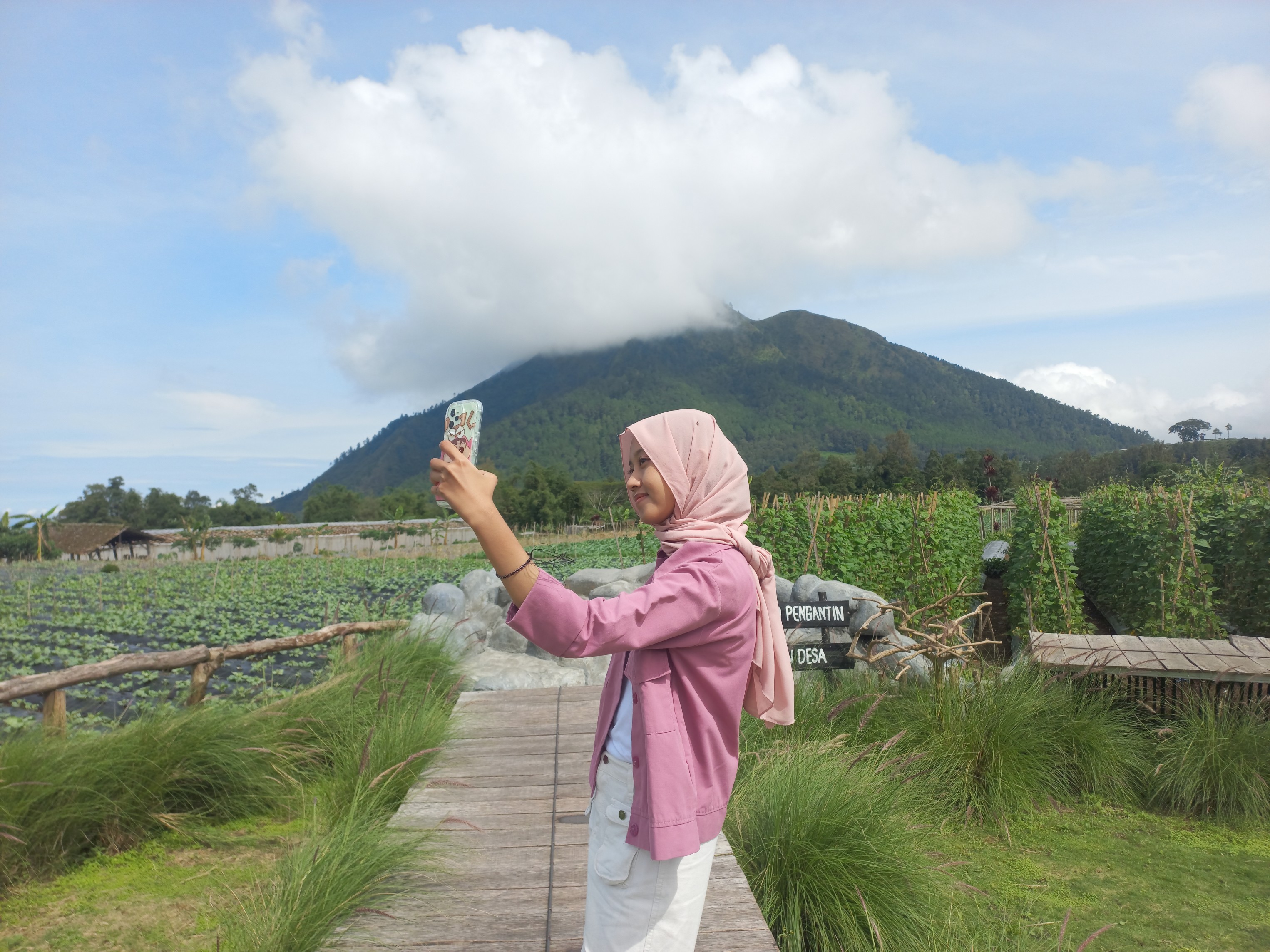 Pengunjung selfie dengan pemandangan gunung.