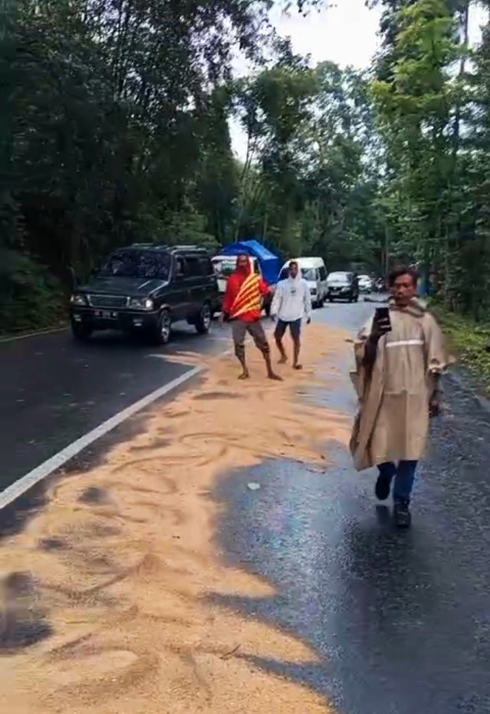 Warga menaburkan serbuk kayu di turunan Jalan Sikoang jalur Wonosobo-Purworejo yang licin terkena tumpahan solar.  &nbsp;