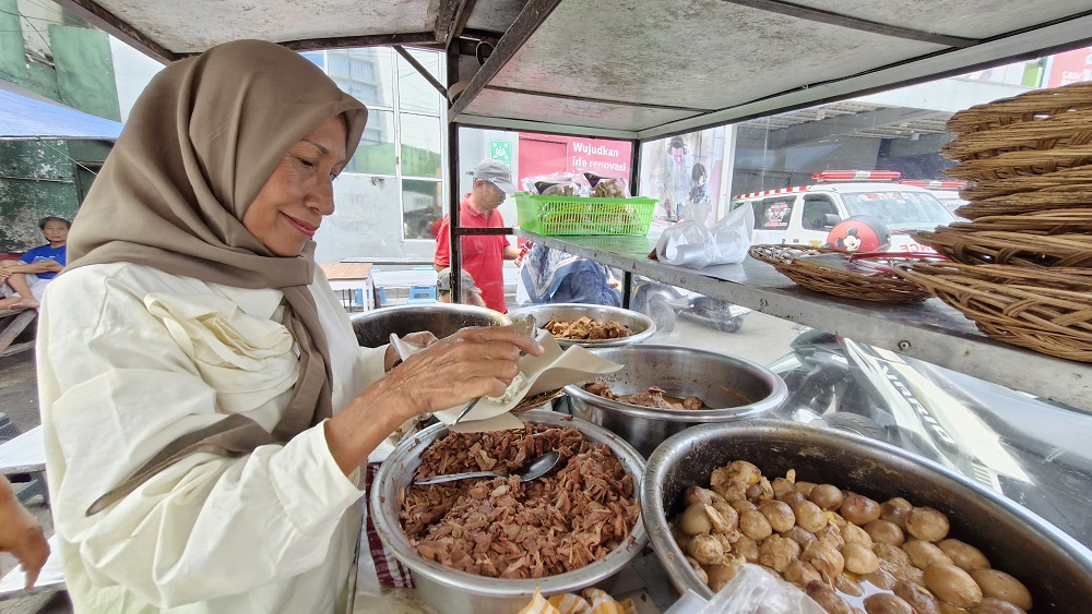 Hetty tengah melayani pembelinya yang memasan gudeg dengan lauk telur dan dada ayam.