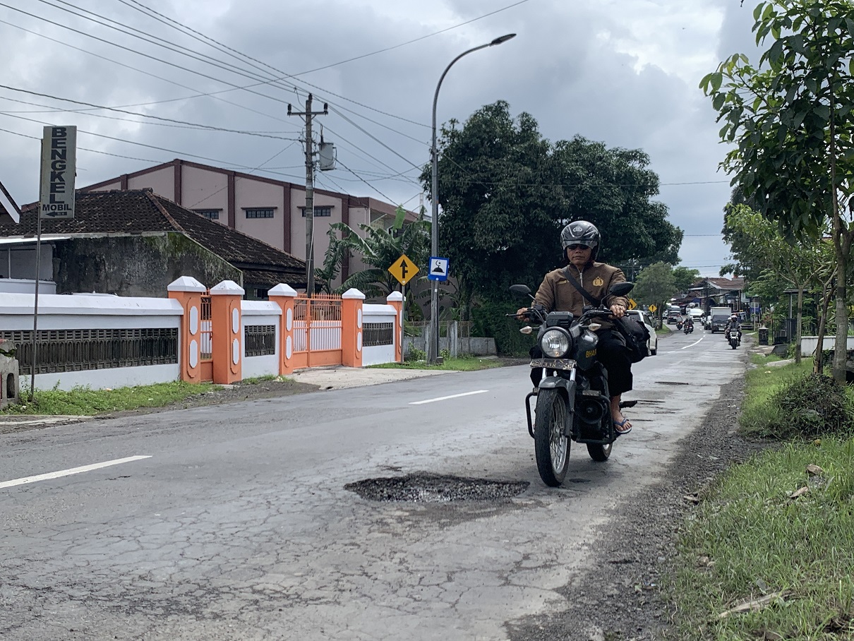 Pengendara melintasi jalan berlubang di kawasan pertigaan Bulu Temanggung.