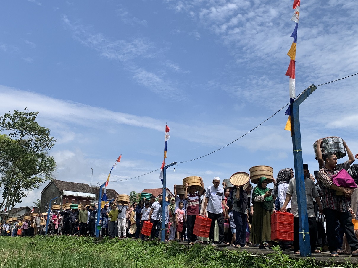 Warga Dusun Demangan, Desa Candimulyo, Kedu membawa makanan menuju makam Eyang Demang, Jumat (7/2/2025).