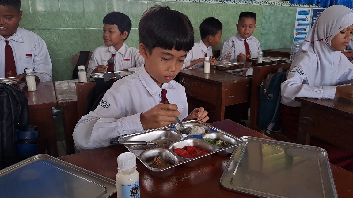 Seorang siswa SD di Magelang dengan lahap menikmati menu makan dari program makan bergizi gratis.