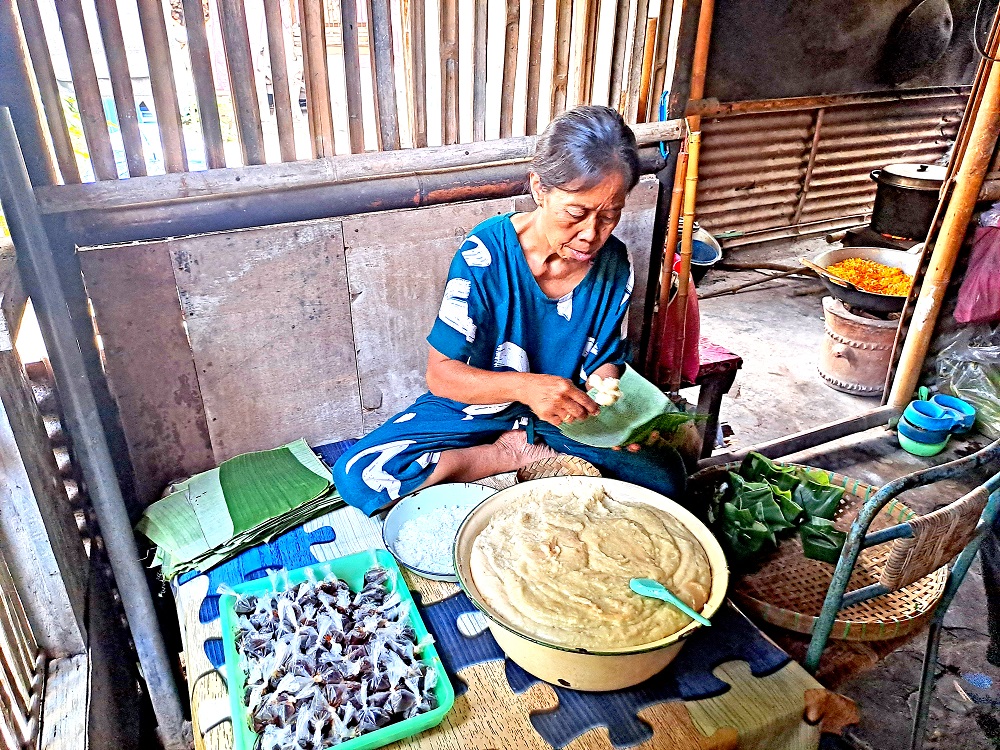 Kasmirah saat membungkus jemunak dengan daun pisang.  &nbsp;