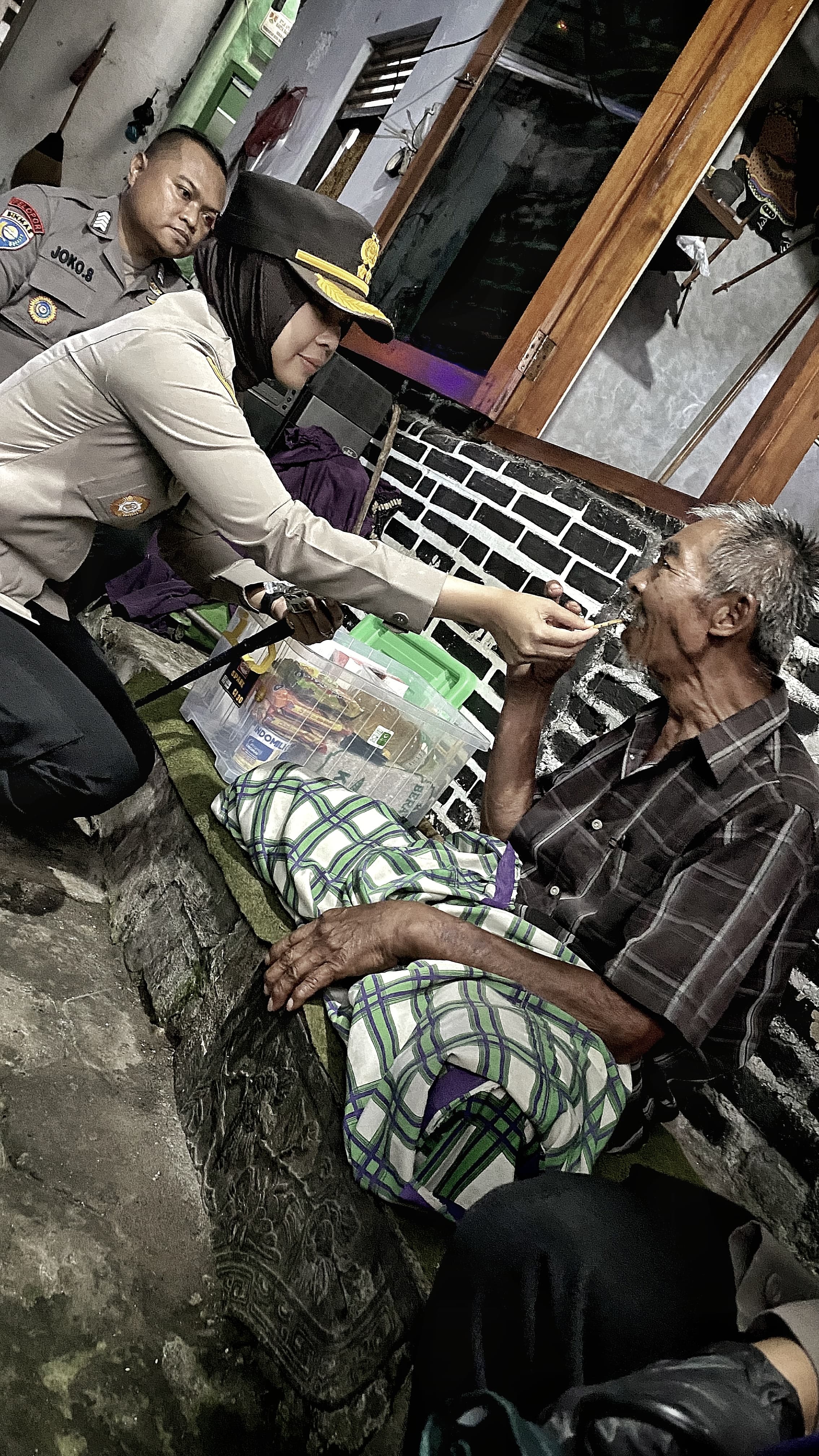 Kapolres Magelang Kota AKBP Anita Indah Setyaningrum menyuapi biskuit kepada Slamet yang tengah sakit, warga di Kampung Tidar Baru, Magersari, Kota Magelang, Jumat (13/3/2025).