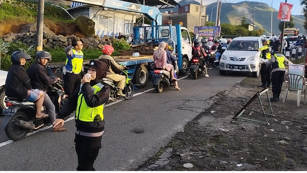 Anggota Polres Wonosobo melakukan pengaturan arus lalu lintas di tanjakan lima belas persen, Dieng yang padat kendaraan.