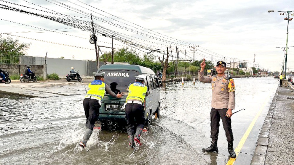 Petugas Satlantas Polres Demak mendorong mobil yang mogok di jalan raya pantura Sayung, Sabtu (5/4/2025).