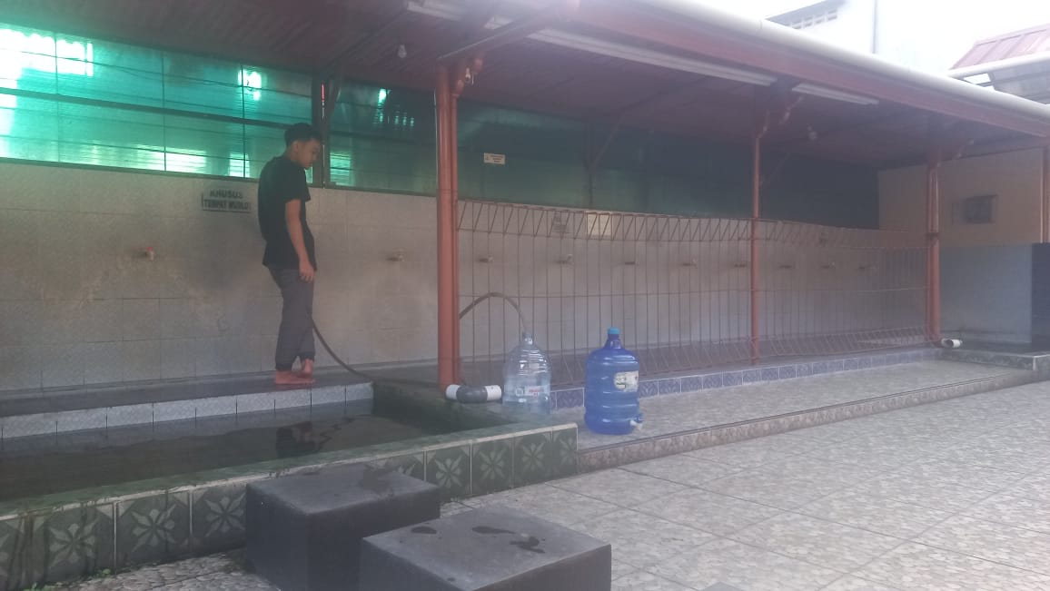 Warga Sudagaran Sapuran mengambil air dari musala setempat setelah air PDAM mati karena pipa terkena alat berat proyek drainase.