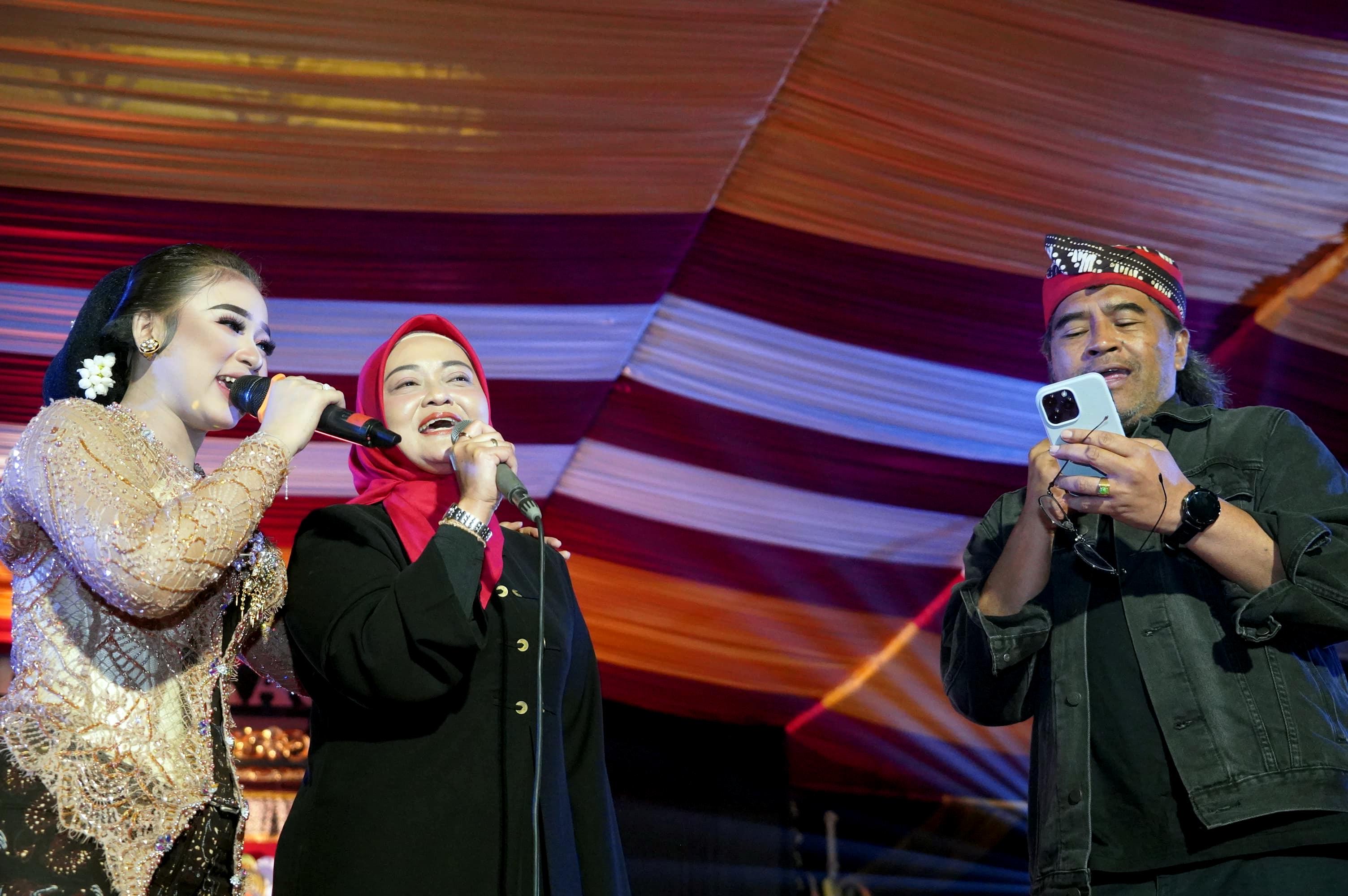 Bupati Agus Setyawan bersama istri, Panca Dewi unjuk suara bersama penyanyi Niken Salindri di acara Regeng Suro di Dusun Bakal, Desa Campurejo, Tretep, Minggu  (27/7/2025).
