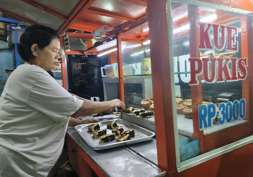 Retno Kustina sedang menyusun kue pukis yang baru matang ke dalam etalase